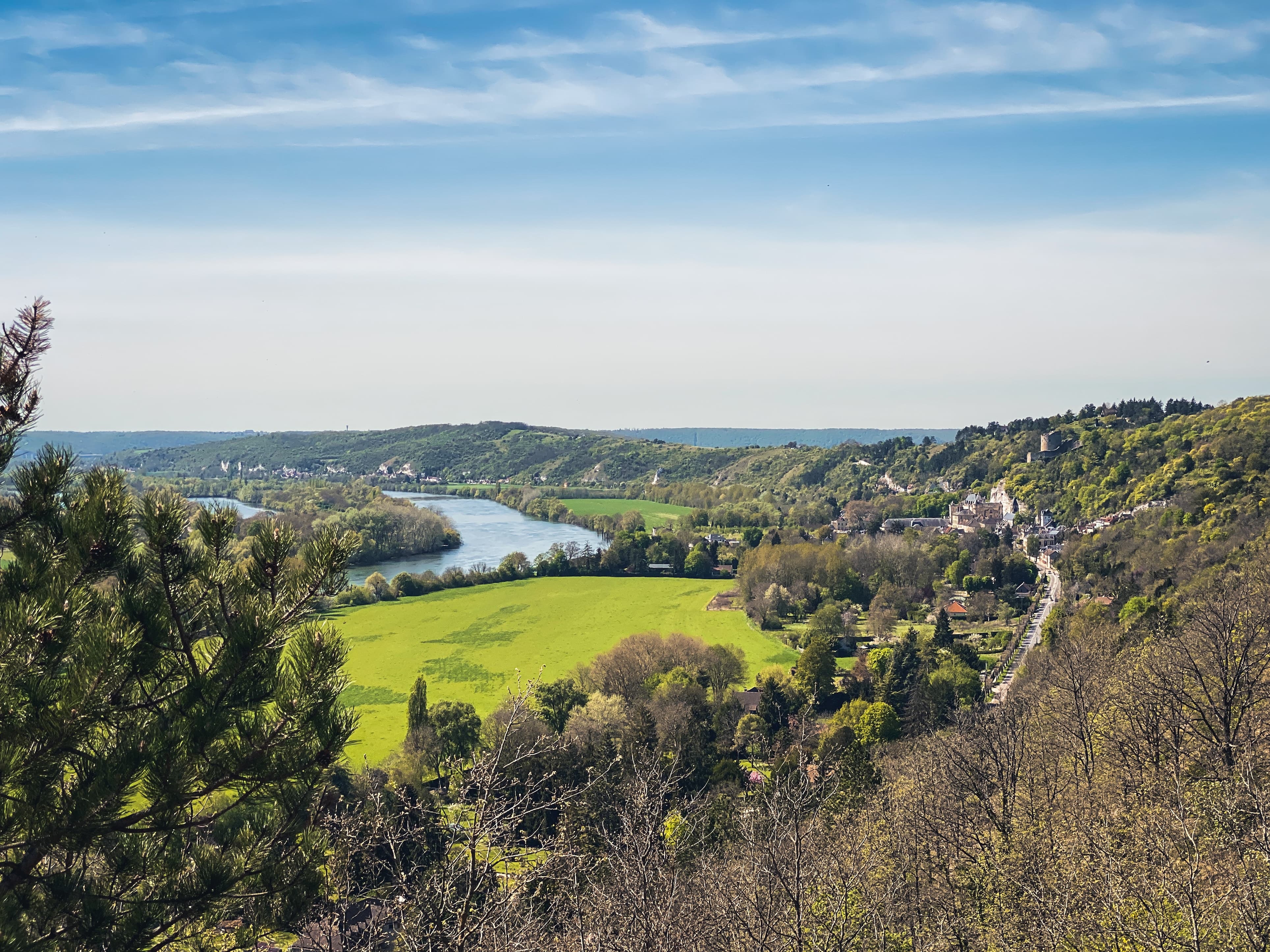 Vu de la Seine en hauteur entre deux collines. Au second plan, la Seine passe devant le Château de La Roche-Guyon.