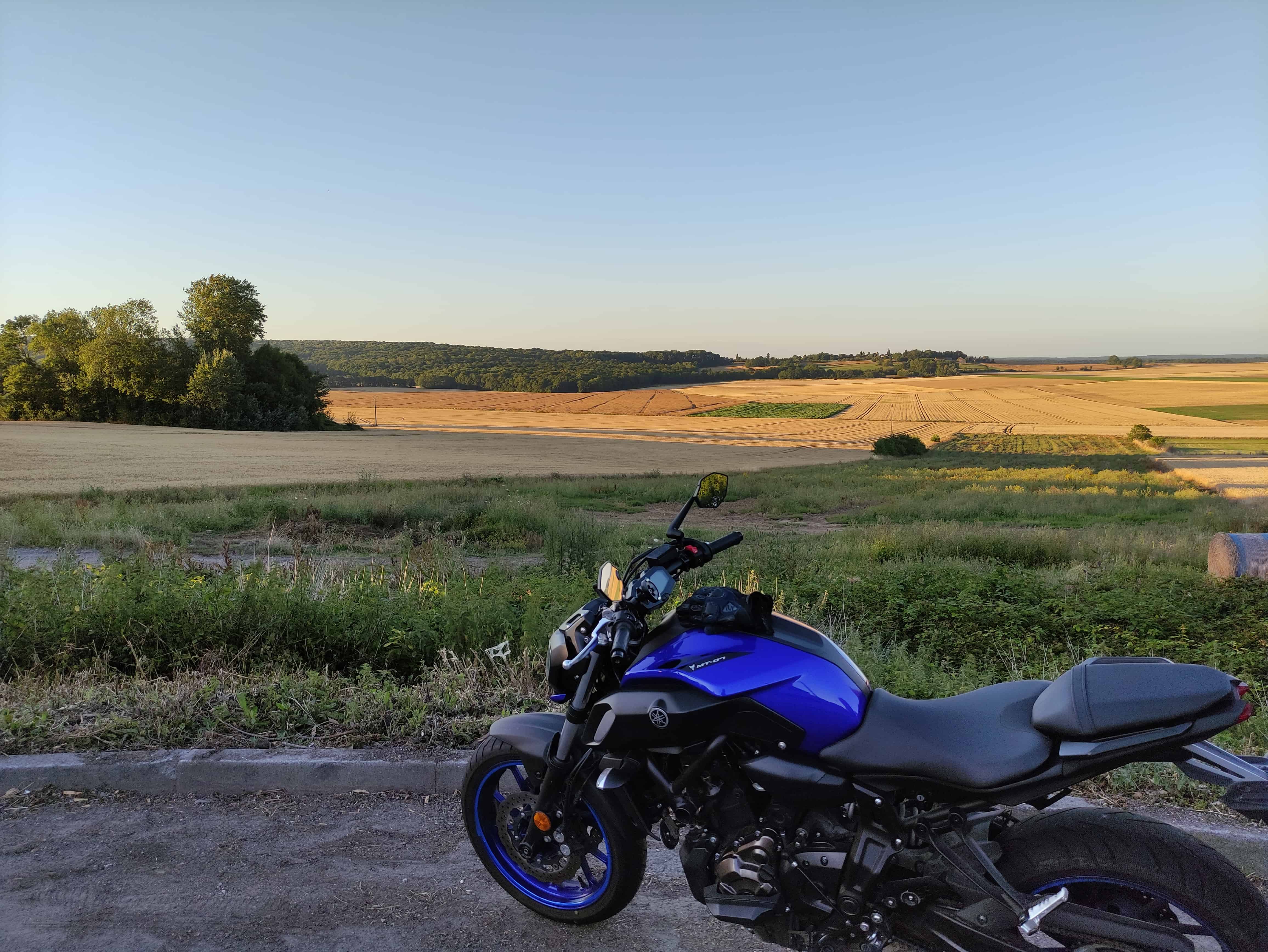 Photo d'une moto bleue devant des champs dans l'Oise.