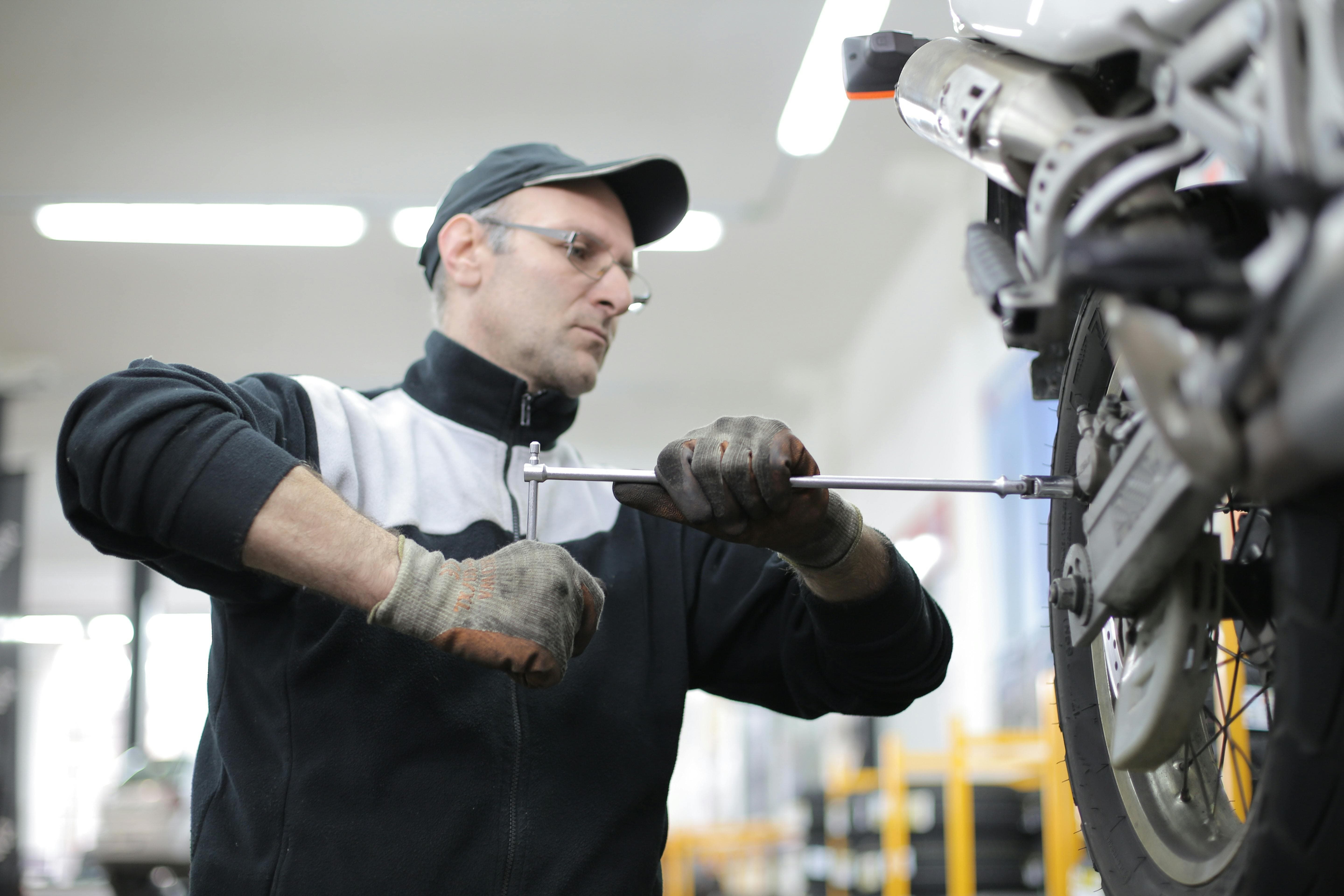 Photo d'un garagiste moto effectuant l'entretien d'un véhicule motorisé